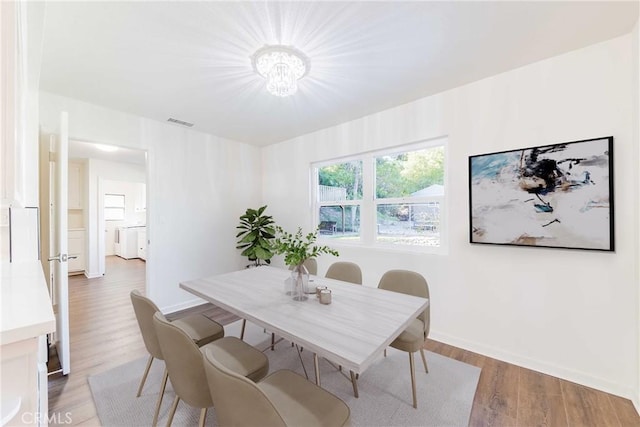 dining space with washer / clothes dryer, visible vents, baseboards, and wood finished floors