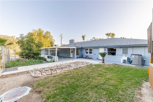 back of property with central AC, a lawn, fence, and stucco siding