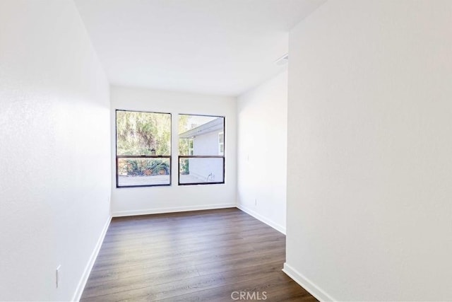 unfurnished room featuring dark wood-style floors and baseboards