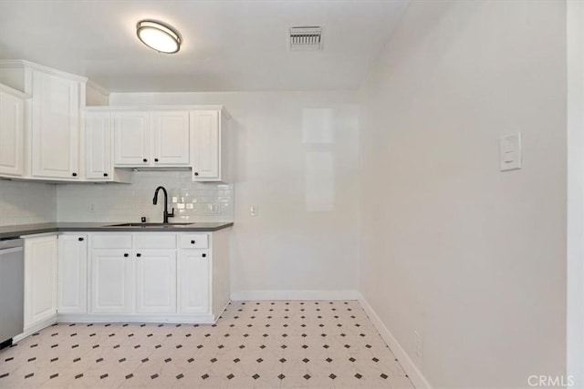 kitchen featuring dark countertops, visible vents, white cabinets, and a sink