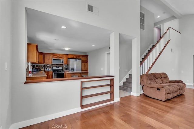 kitchen with light wood finished floors, visible vents, appliances with stainless steel finishes, open floor plan, and a peninsula