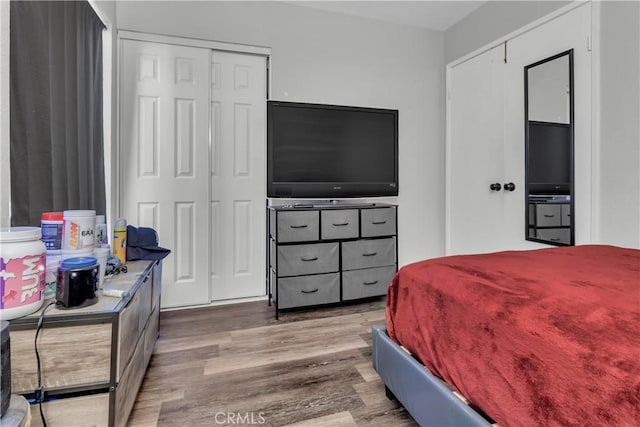 bedroom with multiple closets and wood finished floors