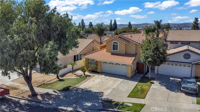 view of front of property with stucco siding, concrete driveway, fence, a mountain view, and a tiled roof