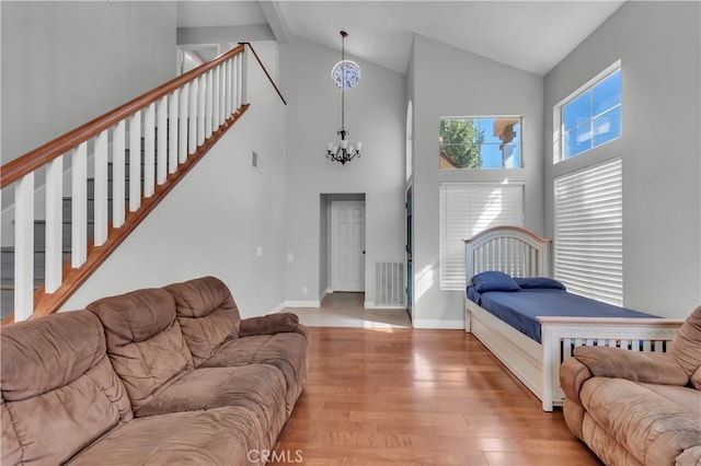 bedroom featuring a notable chandelier, visible vents, baseboards, light wood-type flooring, and beamed ceiling