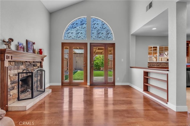 foyer featuring a fireplace, wood finished floors, visible vents, and a healthy amount of sunlight