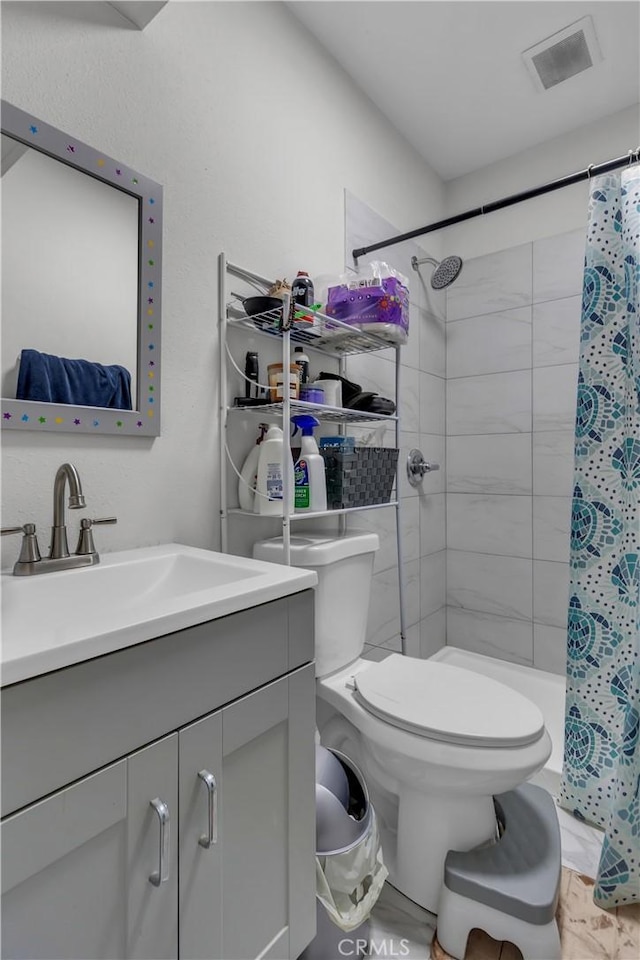 full bathroom with toilet, visible vents, tiled shower, and vanity