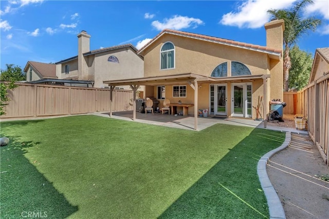 back of house featuring a yard, a chimney, stucco siding, a patio area, and a fenced backyard