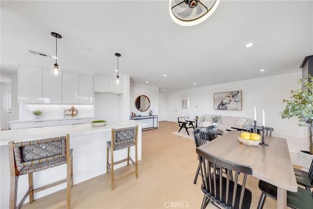 dining area with light wood-style floors, visible vents, and recessed lighting