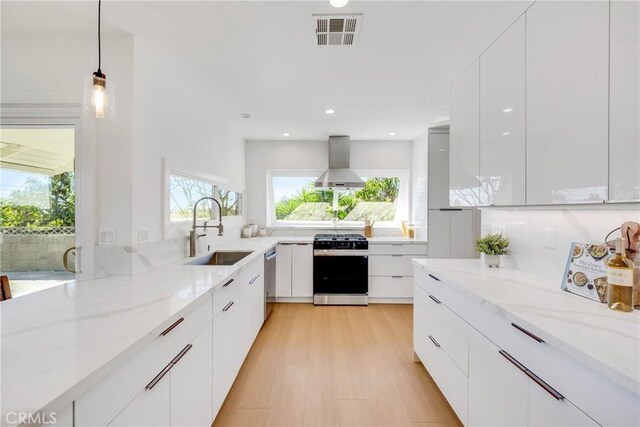 kitchen featuring a sink, wall chimney exhaust hood, modern cabinets, and gas range oven