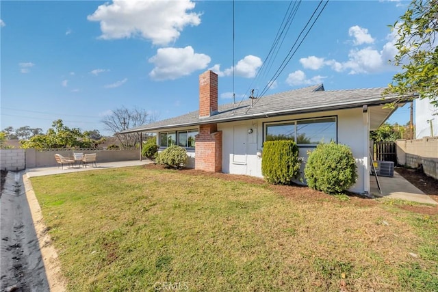 back of house with a patio, a chimney, fence, a yard, and central AC