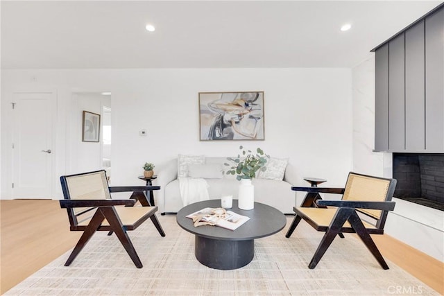 living area featuring recessed lighting, light wood finished floors, and a premium fireplace