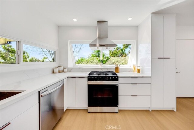 kitchen featuring wall chimney range hood, stainless steel dishwasher, modern cabinets, and range with gas cooktop