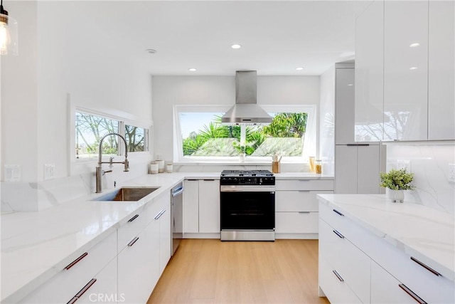 kitchen with dishwasher, modern cabinets, wall chimney range hood, a sink, and gas stove