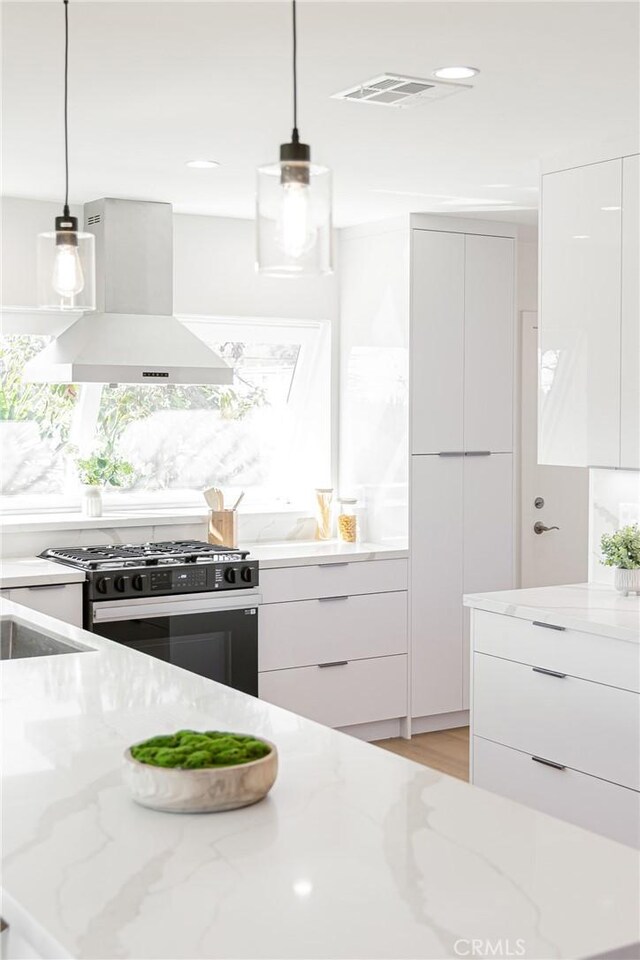 kitchen with range with gas stovetop, modern cabinets, and wall chimney range hood