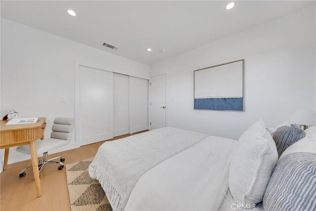 bedroom featuring a closet, recessed lighting, wood finished floors, and visible vents