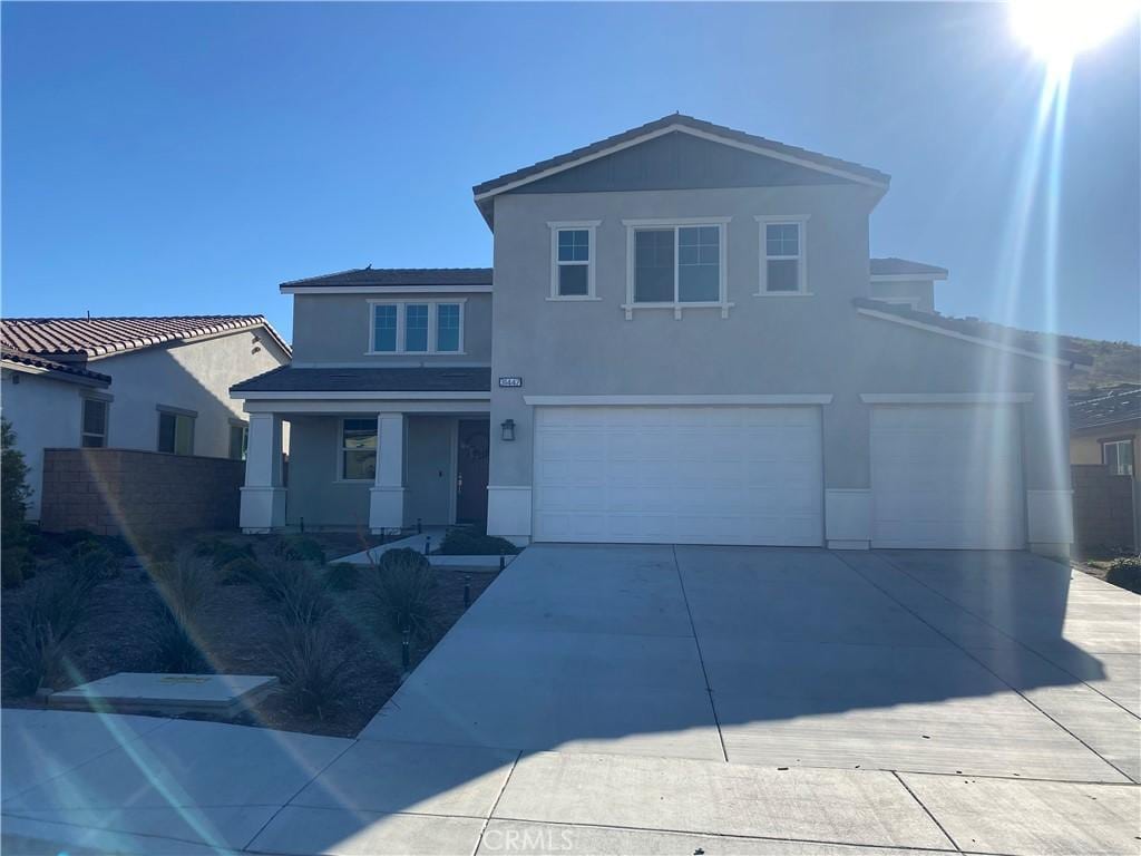 traditional-style home with a garage, concrete driveway, a porch, and stucco siding