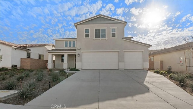 view of front facade featuring concrete driveway, an attached garage, and stucco siding