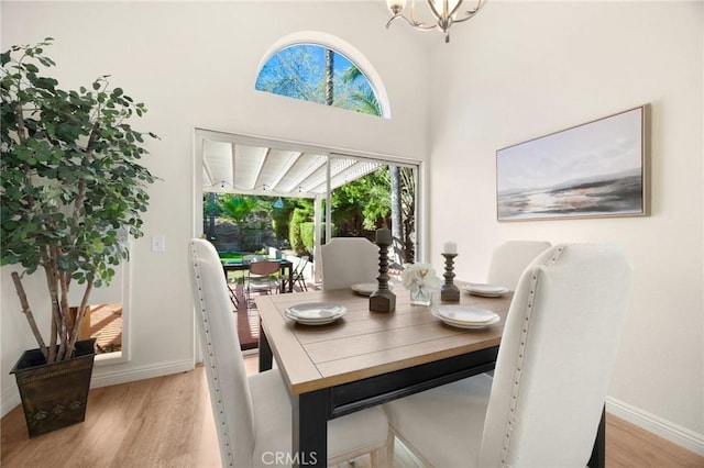 dining room with a chandelier, light wood-style flooring, and baseboards