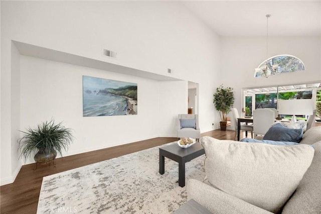 living room with dark wood-style floors, visible vents, a notable chandelier, and baseboards