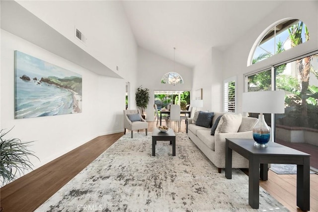 living room with high vaulted ceiling, a wealth of natural light, visible vents, and wood finished floors