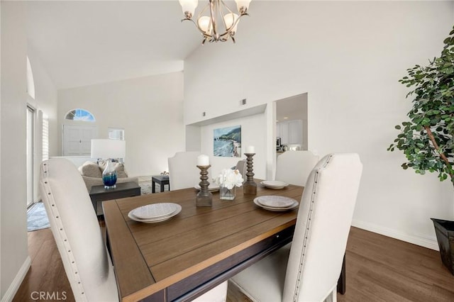 dining room with high vaulted ceiling, dark wood-style flooring, and an inviting chandelier