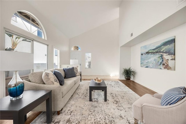 living area featuring high vaulted ceiling, visible vents, and light wood-style floors