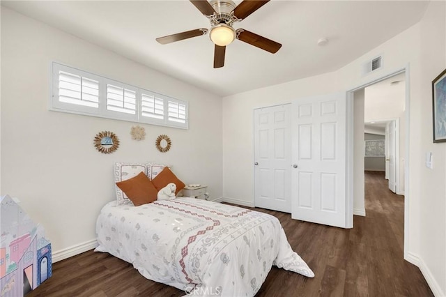 bedroom with a closet, visible vents, dark wood-type flooring, ceiling fan, and baseboards