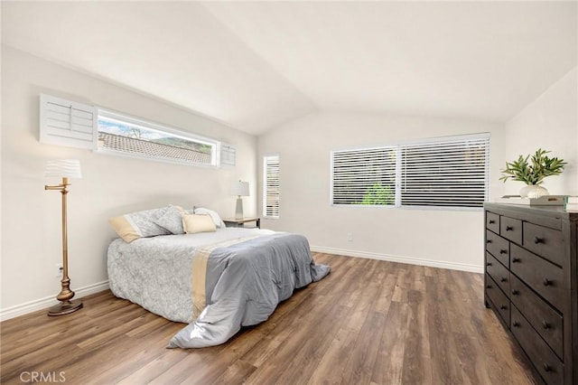 bedroom featuring lofted ceiling, baseboards, and wood finished floors