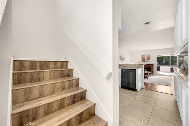 stairway with a brick fireplace, tile patterned flooring, and visible vents