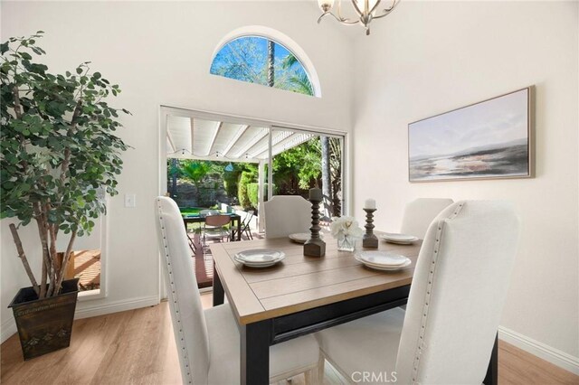 dining room with an inviting chandelier, light wood-style flooring, and baseboards