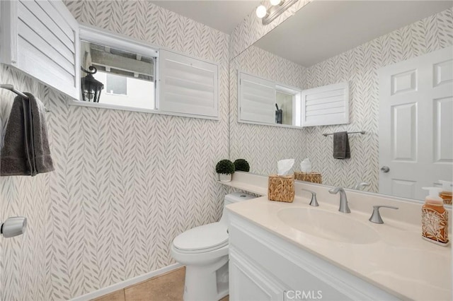 half bath with tile patterned floors, vanity, toilet, and wallpapered walls