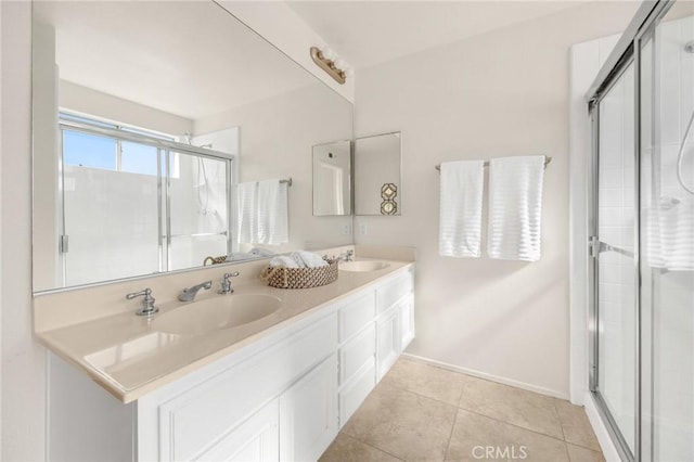 bathroom featuring a stall shower, double vanity, a sink, and tile patterned floors