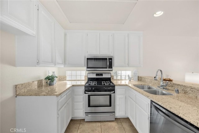 kitchen featuring stainless steel appliances, light tile patterned flooring, a sink, and white cabinets