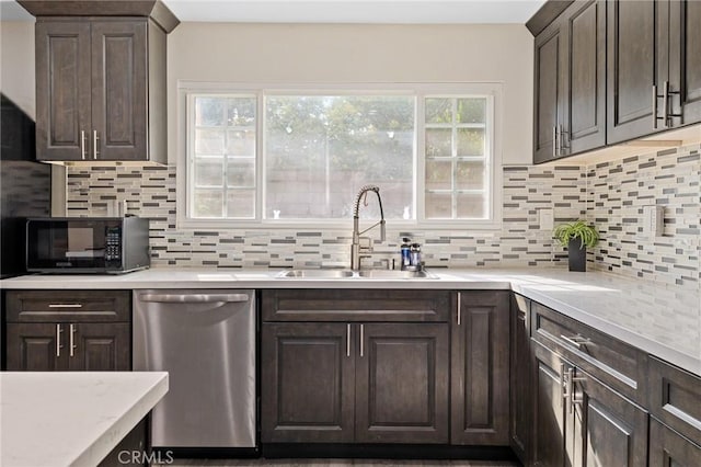 kitchen featuring black microwave, dark brown cabinetry, a sink, light countertops, and stainless steel dishwasher