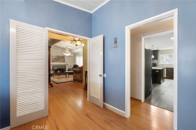 hall with light wood-style floors, baseboards, and crown molding