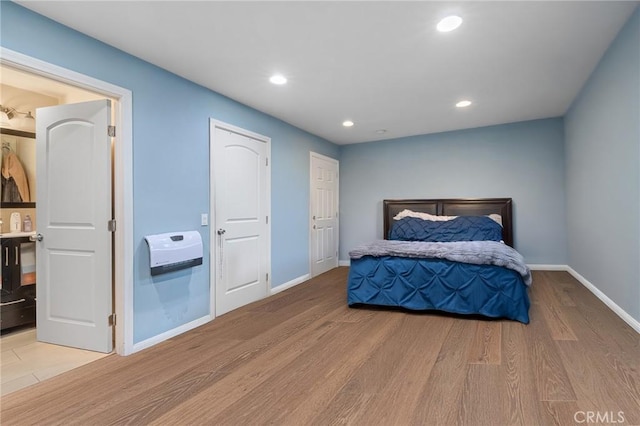 bedroom with baseboards, recessed lighting, light wood-type flooring, and heating unit