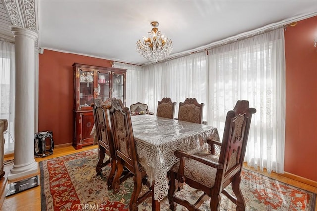 dining space featuring decorative columns, baseboards, ornamental molding, wood finished floors, and a chandelier