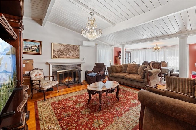 living room with a chandelier, a brick fireplace, decorative columns, and lofted ceiling with beams