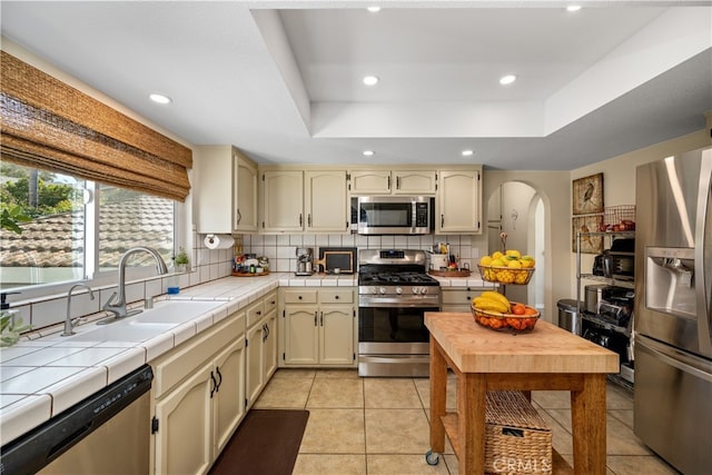 250 Stagecoach Rd, Arroyo Grande, CA 93420 - kitchen featuring stainless steel appliances, a sink, arched walkways, cream cabinets, and decorative backsplash