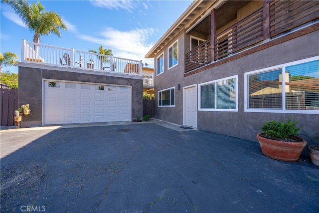 view of property exterior featuring a detached garage, a balcony, and stucco siding