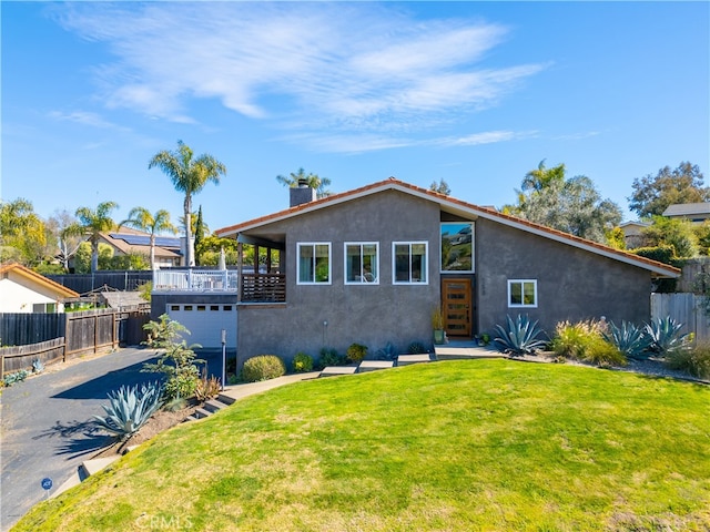 view of front of property featuring aphalt driveway, a chimney, stucco siding, fence, and a front lawn