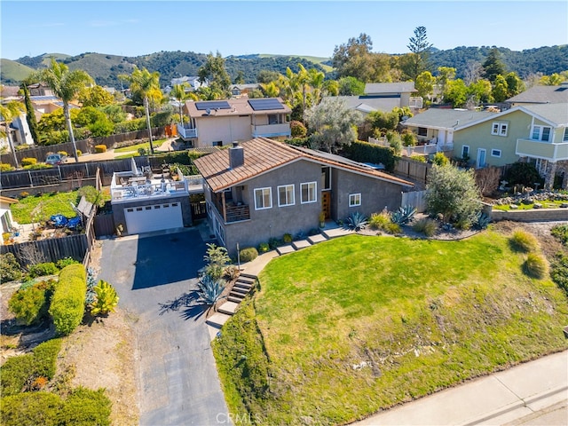 view of front of house with aphalt driveway, fence, a residential view, stucco siding, and a front lawn