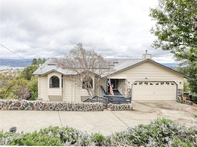 view of front of property with driveway, a chimney, and an attached garage