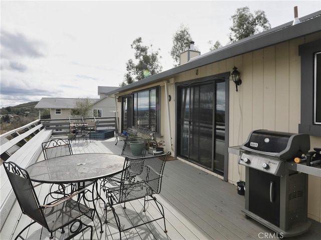 wooden deck with outdoor dining area and area for grilling