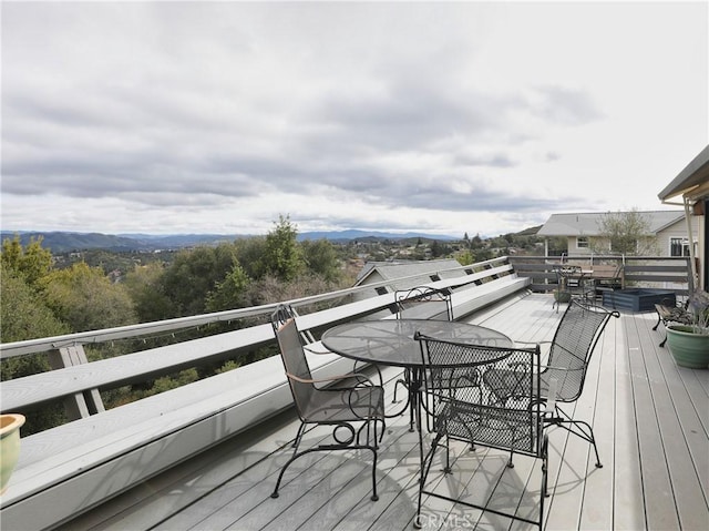 wooden deck featuring outdoor dining space and a mountain view