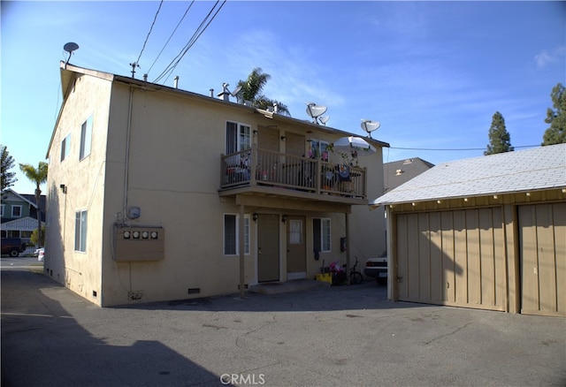 back of house featuring crawl space, a balcony, and stucco siding