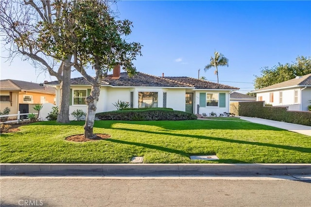 ranch-style home with a front yard, fence, and stucco siding