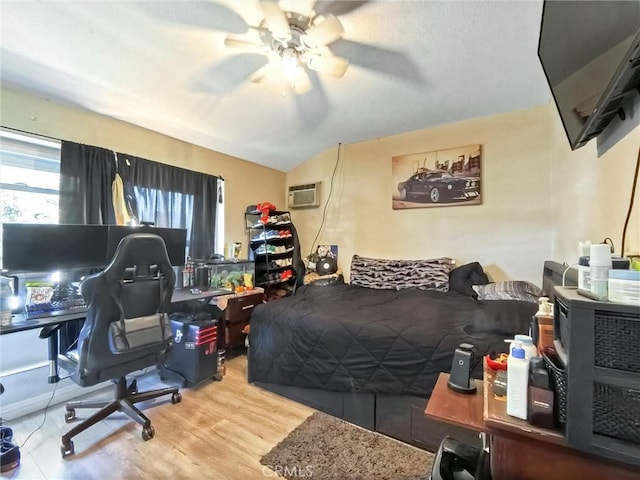 bedroom with a wall unit AC, wood finished floors, and a ceiling fan