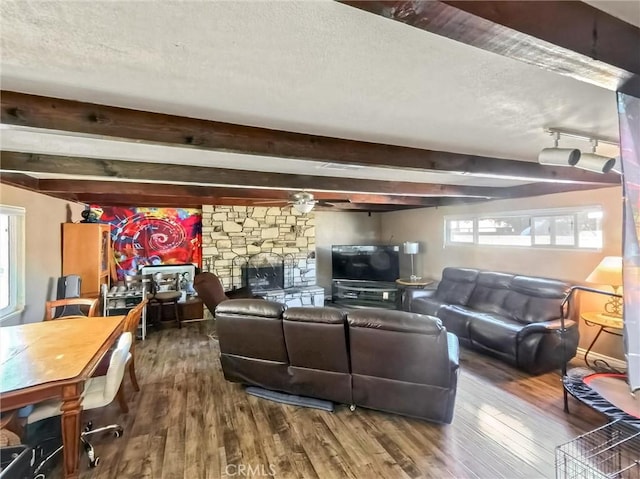 living room with beam ceiling, a fireplace, a textured ceiling, and wood finished floors