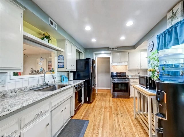 kitchen with under cabinet range hood, a sink, visible vents, white cabinets, and black appliances